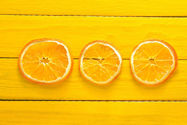 Шматочки сушеного апельсина на жовтому дерев'яному столі. Концепція фруктів. Тенденція мінімалізму. Вид зверху
. - Фото, зображення