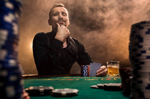 Przystojny Brodaty mężczyzna pije whisky podczas gry w pokera - Zdjęcie, obraz