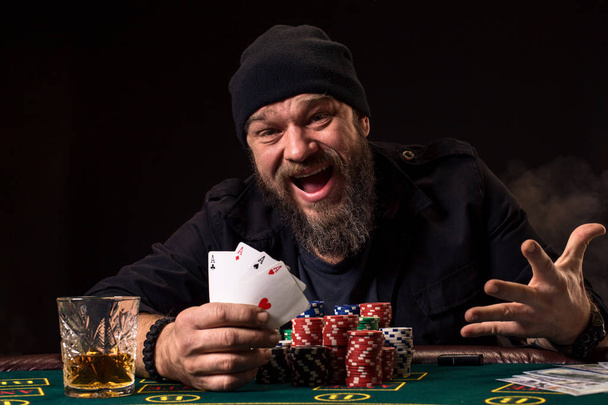 Bearded man drinking whisky while playing poker - Photo, Image