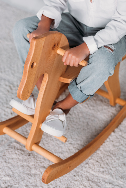 cropped image of african american kid sitting on rocking horse - Foto, afbeelding