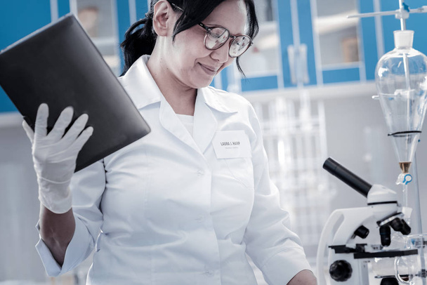 Positive minded scientist using touchpad while working in lab - Foto, Imagen