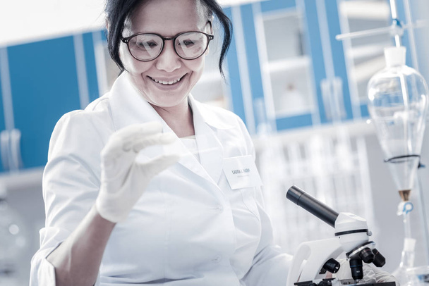Happy scientist smiling while looking at microscope slide - Valokuva, kuva