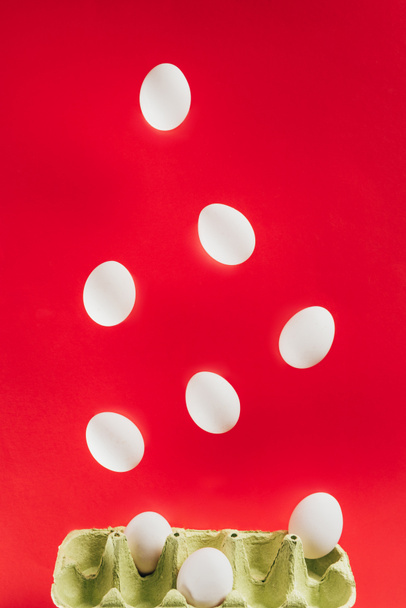 крупним планом вид вирівнювання сирих курячих яєць і картонної ящики ізольовані на червоному
 - Фото, зображення