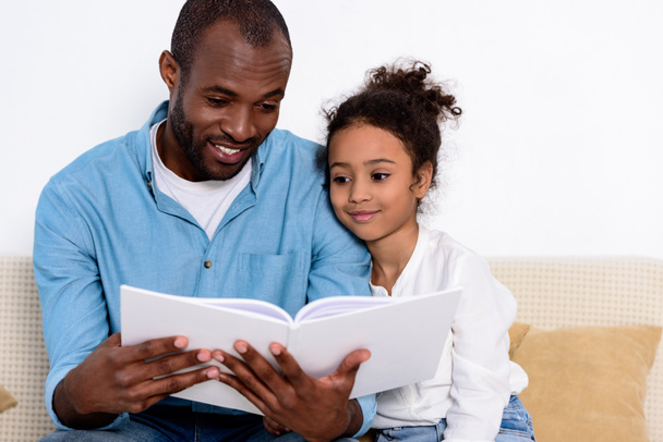 happy african american father reading book to daughter - Fotó, kép