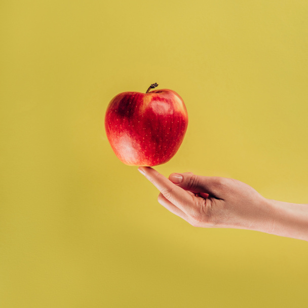 partial view of woman holding apple on finger - Foto, imagen