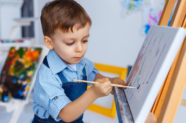 Симпатичный, серьезный и сосредоточенный, белый трехлетний мальчик в синем.
 - Фото, изображение