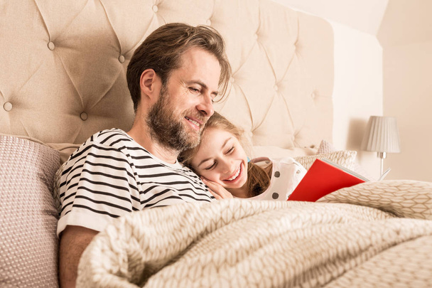 Father and daughter reading a book in a bed - Foto, immagini