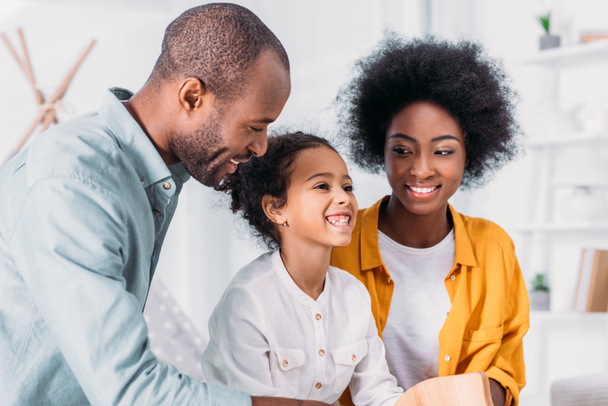 sonrientes afroamericanos padres e hija divirtiéndose en casa
 - Foto, Imagen
