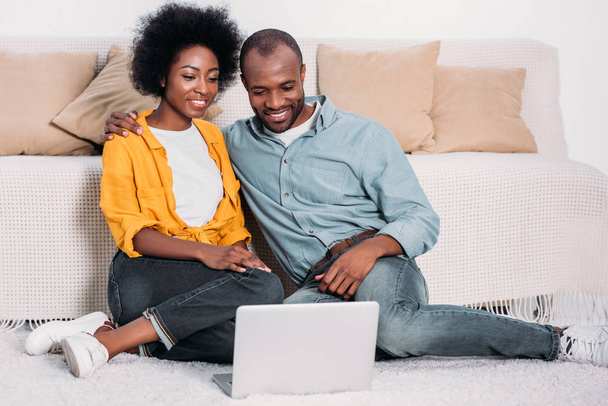 uśmiechający się african american para oglądanie filmu na laptopa w domu  - Zdjęcie, obraz