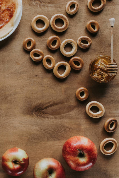 pohled shora sladké bagely, medu a jablka na dřevěný stůl - Fotografie, Obrázek