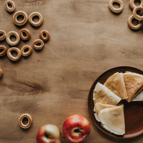 top view of tasty homemade pancakes with apples and bagels on wooden table - Foto, Bild