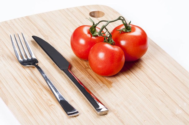 Punaiset tuoreet tomaatit leikkuulaudalla
 - Valokuva, kuva