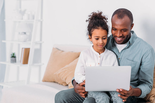 feliz pai e filha afro-americanos usando laptop em casa
 - Foto, Imagem