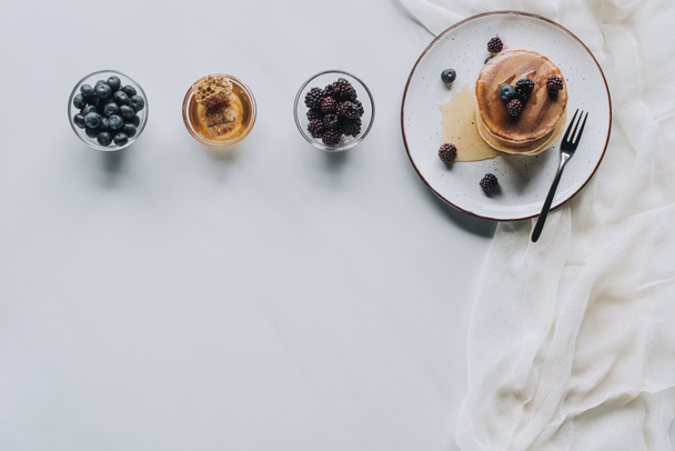 top view of sweet homemade pancakes with honey and fresh berries on grey  - Valokuva, kuva