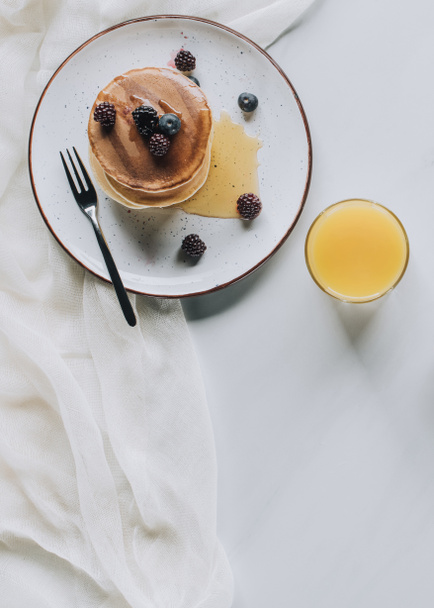 top view of tasty healthy breakfast with homemade pancakes, berries, honey and juice on grey   - Foto, afbeelding