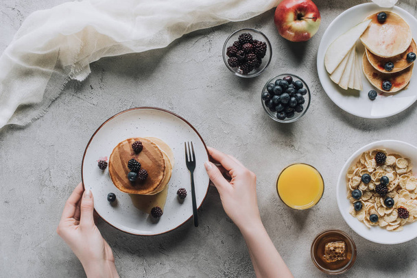 top view of person eating delicious homemade pancakes with berries for breakfast - Foto, Imagem