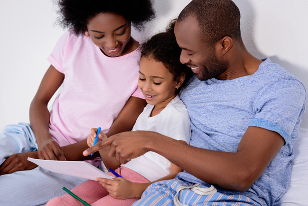 Африканские американские родители помогают дочери рисовать в альбоме дома
 - Фото, изображение