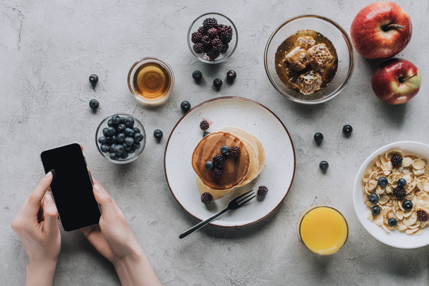 cropped shot of person using smartphone while having healthy tasty breakfast - Foto, afbeelding