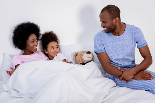 african american parents and daughter in bedroom looking at each other - Photo, Image