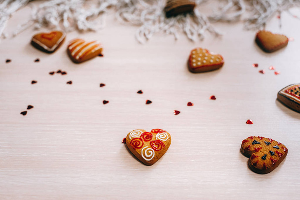 Closeup view of decorated heart shaped cookies laying on beige table with glitter and sackcloth napkin - Foto, afbeelding