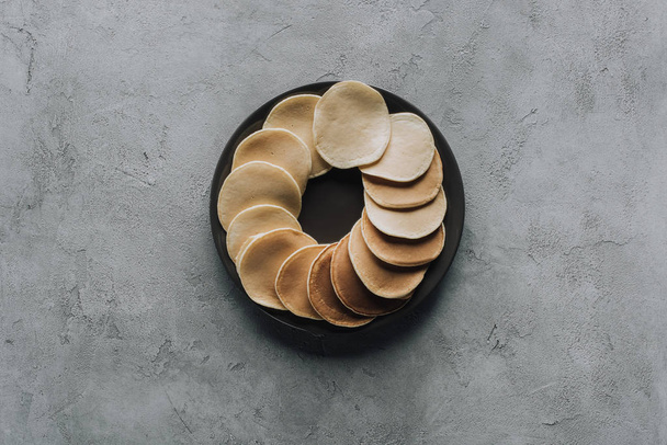 bovenaanzicht van lekkere huisgemaakte pannenkoeken op plaat op grijs - Foto, afbeelding