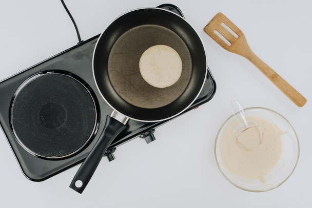 cropped shot of pancake cooking on frying pan and dough in bowl on grey - Fotoğraf, Görsel