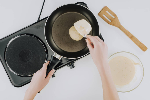 cropped shot of person cooking pancakes on frying pan on grey - Foto, imagen