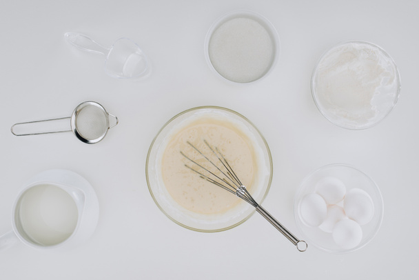 top view of dough and whisk, ingredients and utensils for cooking pancakes isolated on grey - Photo, Image