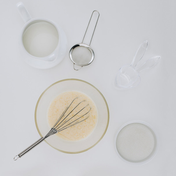 top view of whisk and dough for cooking pancakes isolated on grey - Fotografie, Obrázek
