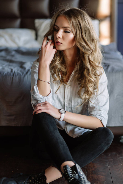 A girl with long blond hair dressed in black jeans, a striped sh - Фото, зображення