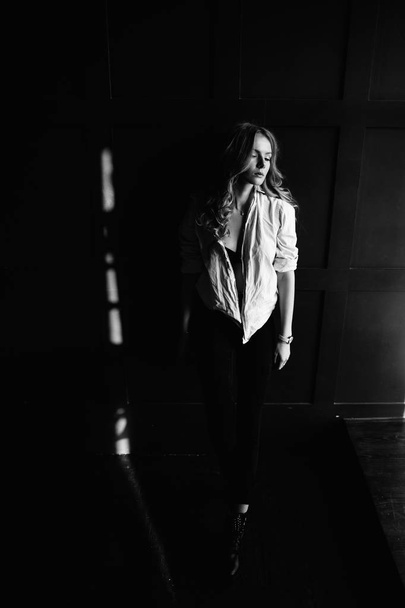 Young beautiful woman model in a white shirt, black jeans, confident, blue background - Fotó, kép