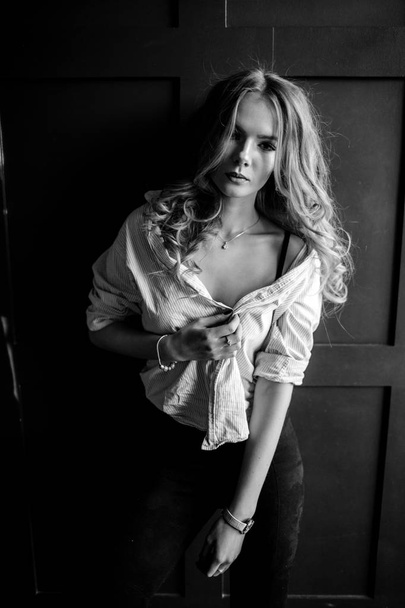 Young beautiful woman model in a white shirt, black jeans, confident, blue background - Fotó, kép