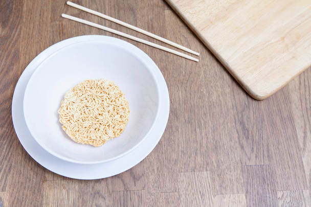 Uncooked Instant Noodles in white bowl and Plate on wooden table - Foto, Imagem