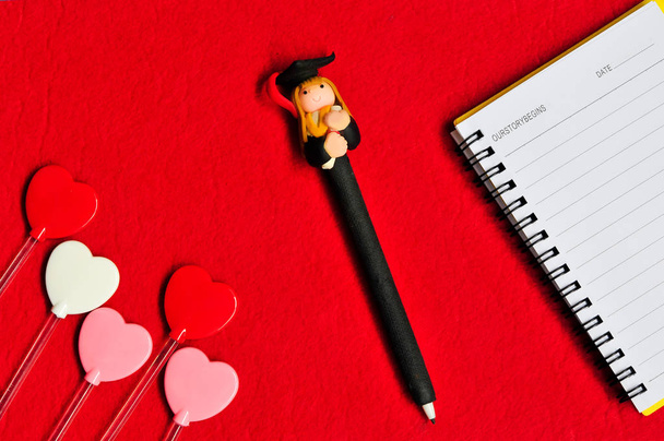 Το Top view σχήματα καρδιάς με αποφοίτηση κούκλα στυλό και σημειωματάριο στο r - Φωτογραφία, εικόνα
