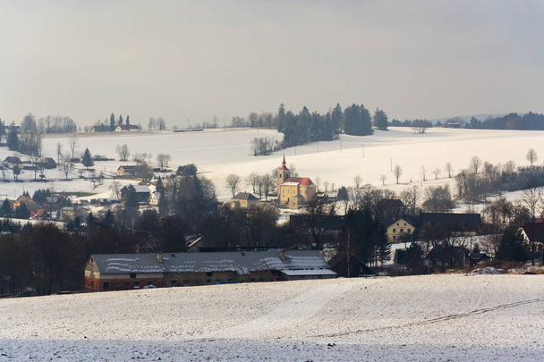 St. Peter- und Paulskirche in Ceske petrovice, verschneites Winterland bei sonnigem Wetter, Tschechische Republik - Foto, Bild