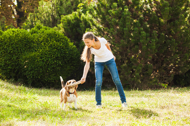 Girl plays with a dog in the yard - Fotoğraf, Görsel