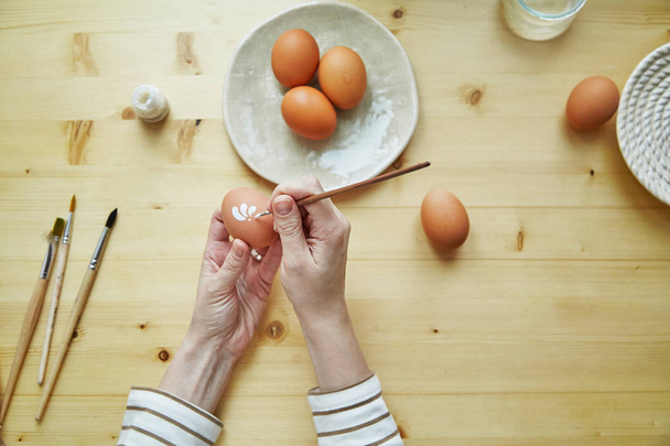 female hands painting egg in white pattern for Easter holiday, close-up   - Foto, Imagen