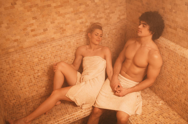 Hermosa pareja joven relajándose en el baño de vapor en el centro de spa
. - Foto, Imagen
