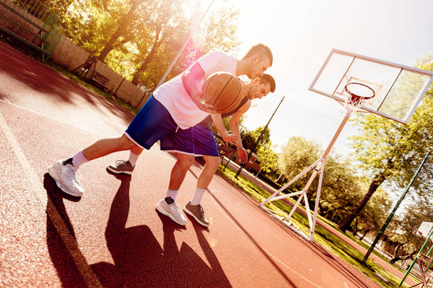 Dos jugadores de baloncesto callejeros entrenando al aire libre. Están haciendo una buena acción.
. - Foto, imagen