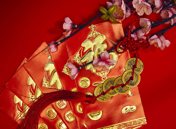 chinese new year festival decorations plum flowers wthi Firecrackers, envelopes, lucky Chinese five gold medals on red with copy space (Foreign text means lucky blessing) - Valokuva, kuva