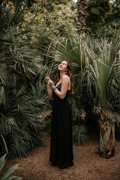 Beautiful woman with black dress among palm trees - Foto, afbeelding