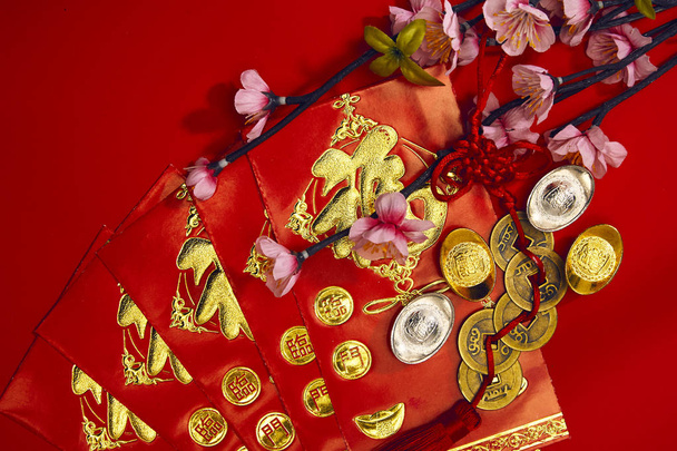 chinese new year festival decorations plum flowers wthi Firecrackers, envelopes, lucky Chinese five gold medals on red with copy space (Foreign text means lucky blessing) - Valokuva, kuva