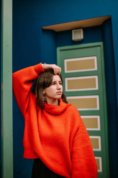 Young woman leaning on a column with red pullover in a colorful house - Fotografie, Obrázek