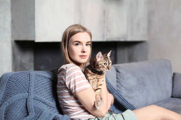 Beautiful young woman with cute cat on sofa at home - Photo, image