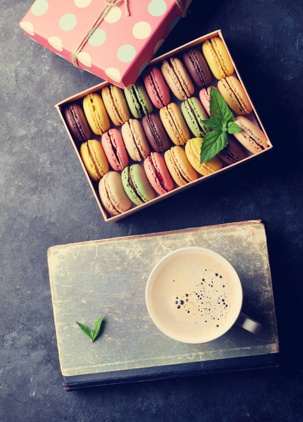 Macaroons coloridos e café na mesa de pedra. Macarons doces na caixa de presente. Vista superior. Retro tonificado
 - Foto, Imagem