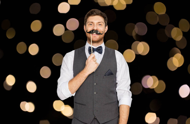 happy young man with fake mustache at party - Фото, изображение
