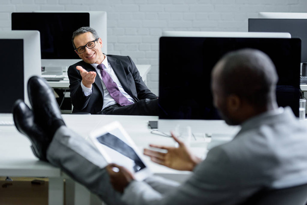 избирательное внимание мультикультурных бизнесменов, беседующих на рабочем месте в офисе
 - Фото, изображение