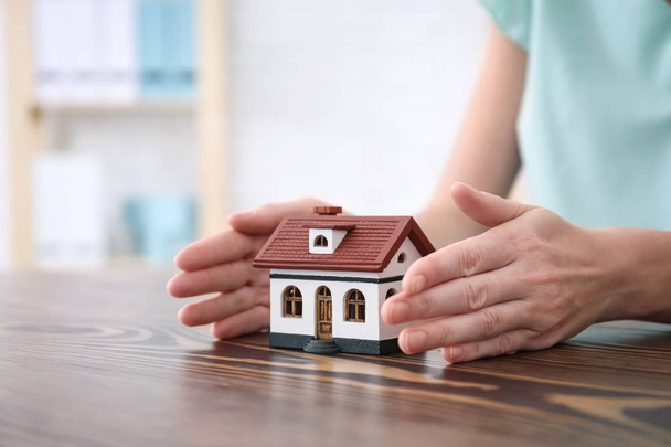 Real estate agent with house model at table. Insurance concept - Photo, Image