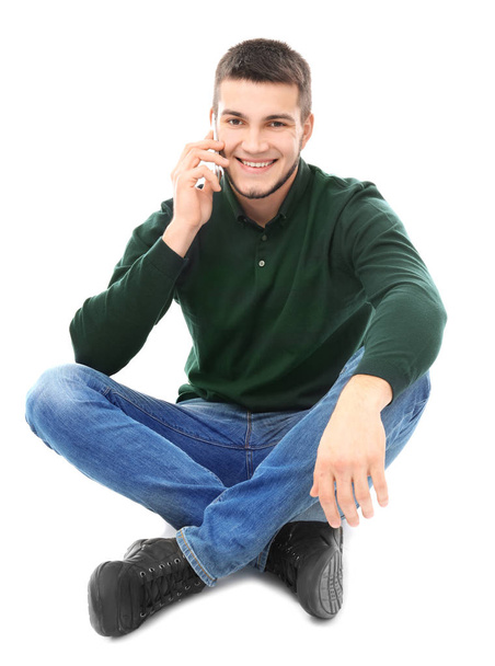 Young man talking on cell phone against white background - Fotografie, Obrázek