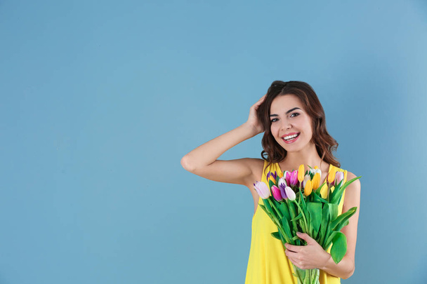 Beautiful woman holding bouquet of tulips on color background - Foto, Bild